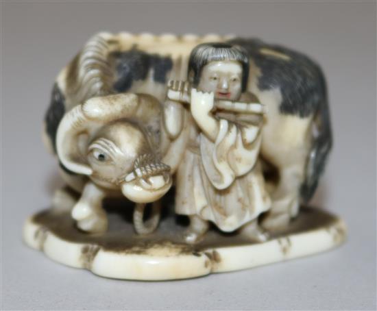 A Japanese ivory netsuke of a figure playing the flute standing by an ox, 19th century, 4.4cm